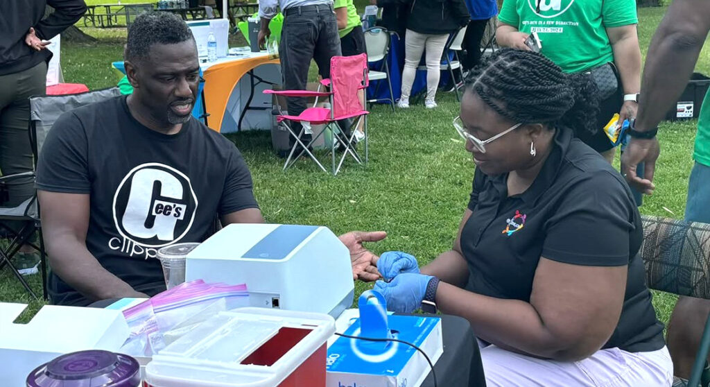 Professor Shiyanbola administers a diabetes blood sugar test to a visiting patient