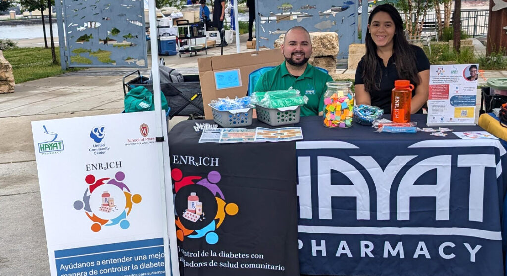 ENRxICH staff members sit outdoors at a booth, ready to assist patients
