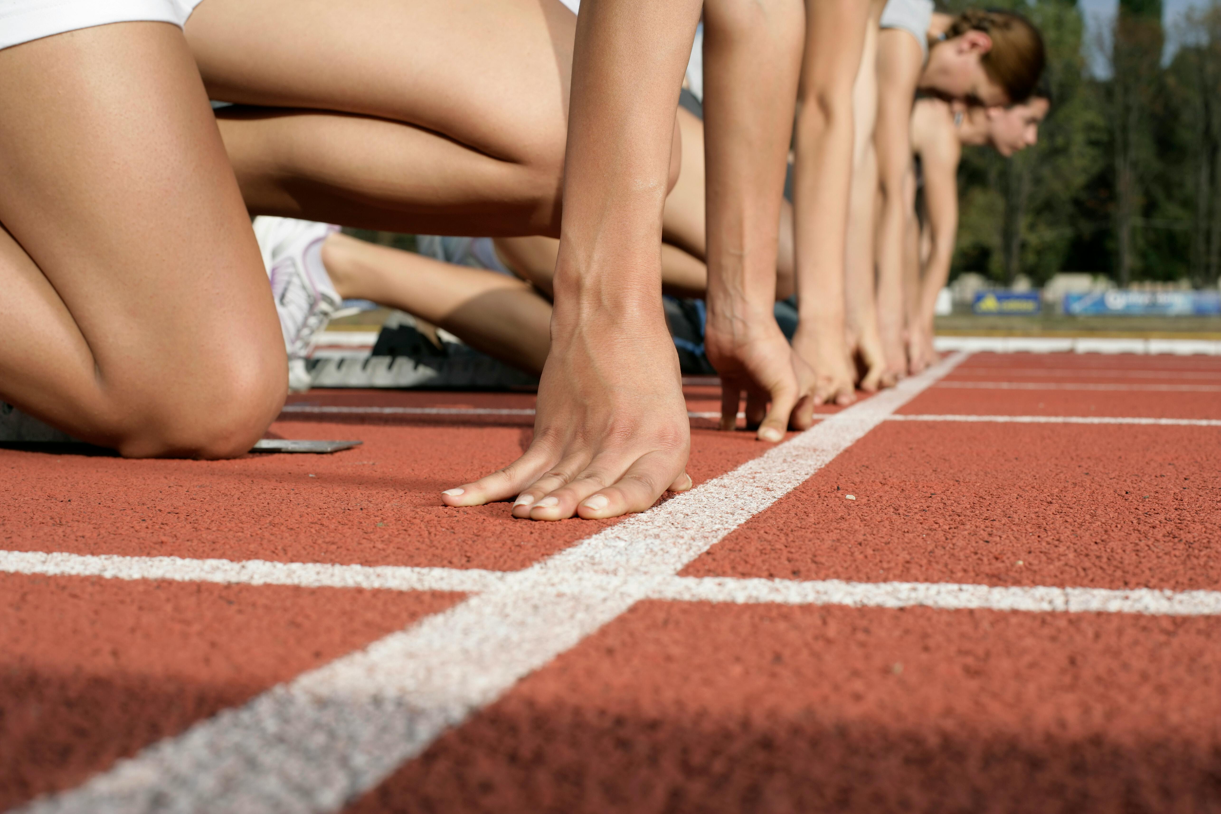 Runners hunch down together at the start line of a race